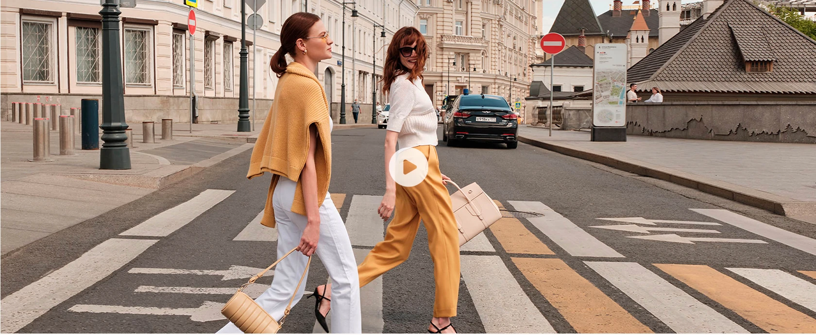 Two women carrying leather handbags on a city street