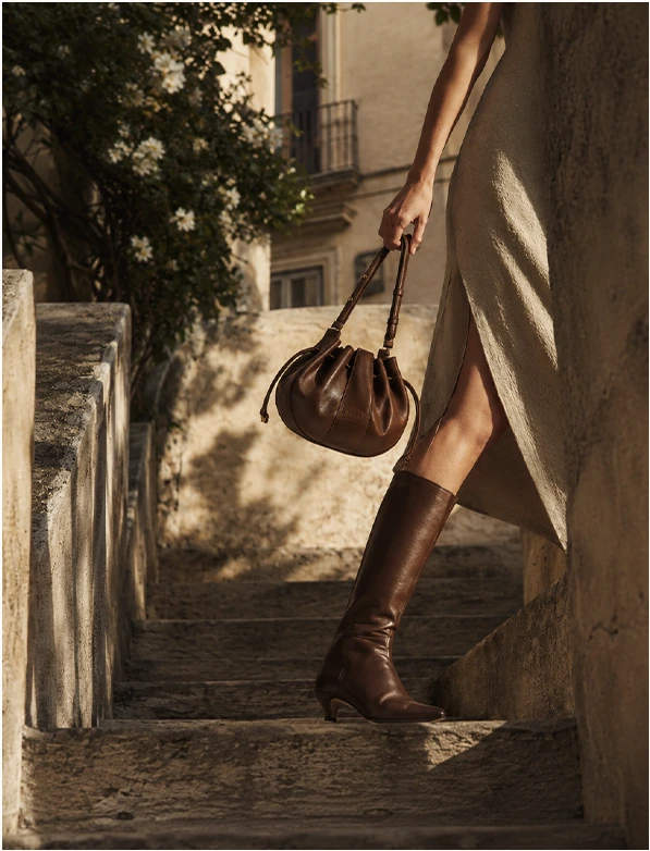 Woman carrying a brown handbag on stone steps